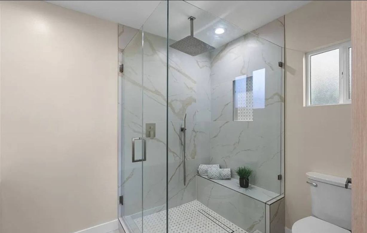 Marble walk-in shower with glass enclosure and bench
