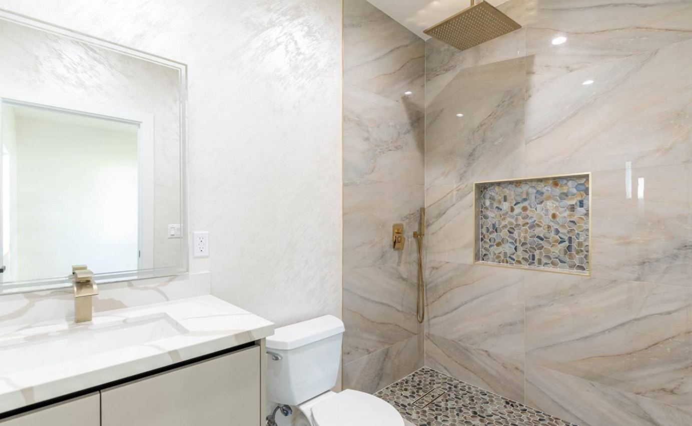Marble bathroom with brass fixtures and mosaic tile niche