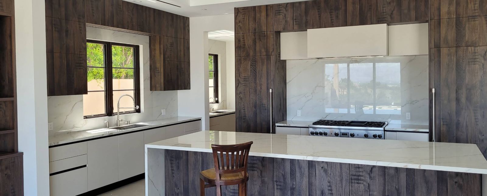 Luxury kitchen with dark wood cabinetry and marble waterfall island