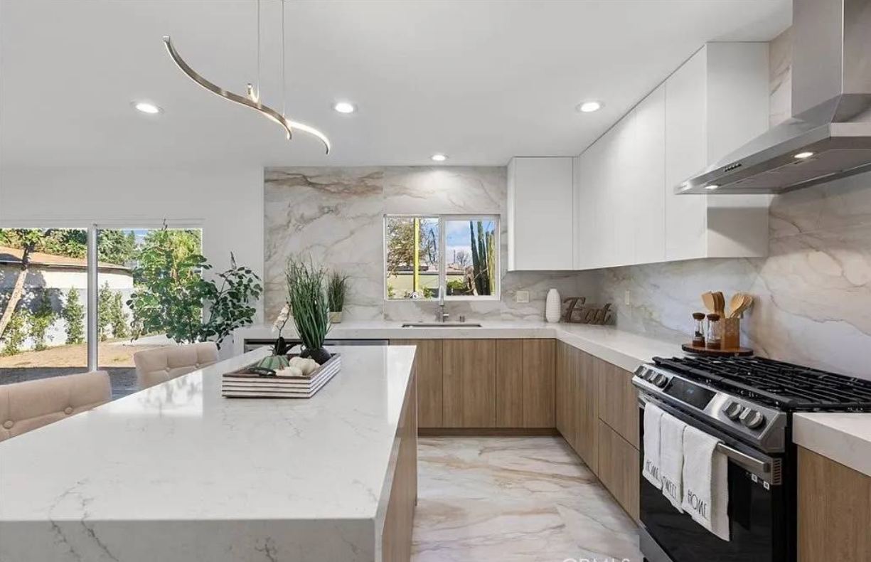 Bright kitchen with marble waterfall island and wood cabinets